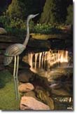 Outdoor garden lights being use to light a crane and waterfall feature.